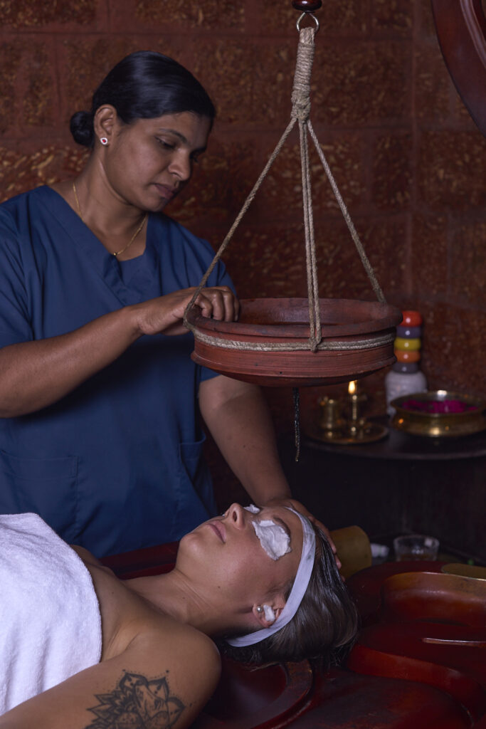 "Traditional Ayurvedic Dhara therapy in progress, with warm medicated oil flowing continuously on the forehead, promoting relaxation and mental clarity at Indeevara Retreat."